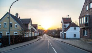 Asphalt road in the town, beautiful houses and sunset, rural landscape.